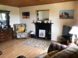 sala de estar con chimenea, sofá y silla en Granda's House - A Home from Home near Carlingford, en Carlingford
