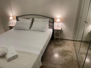 een slaapkamer met een groot wit bed en 2 tafels bij Siel seaside apartment in Perea