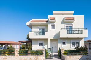 a white house with a fence in front of it at Amphitrite Villa in Gennadi