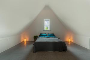 a bedroom with a bed with blue pillows and a window at Casa Morreni, luxe villa met sauna in Voorthuizen