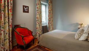 sypialnia z łóżkiem, czerwonym krzesłem i oknem w obiekcie Hôtel-Résidence La Rubanerie w mieście Schirmeck