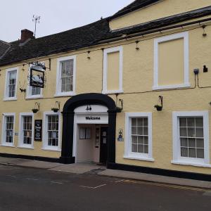 un edificio amarillo con un arco en una calle en Swan Hotel, en Wotton-under-Edge