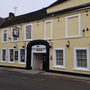 a yellow building with an archway in a street at Swan Hotel in Wotton under Edge
