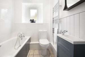 a white bathroom with a toilet and a sink at Campsie Cottage in Ancrum