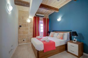 Tritoni Harbour suites - Valletta في فاليتا: غرفة نوم مع سرير مزدوج كبير مع جدران زرقاء