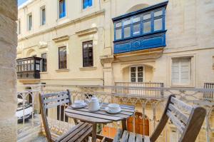 Tritoni Harbour suites - Valletta في فاليتا: طاولة وكراسي على شرفة مع مبنى