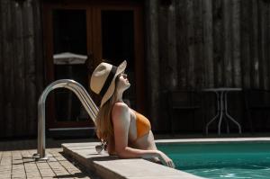 a woman in a hat sitting next to a swimming pool at Eden Resort in Yasnogorodka