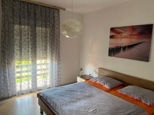 a bedroom with a bed and a large window at Apartment Ružica in Sukošan