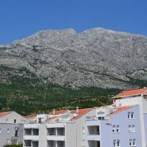 ein weißes Gebäude mit einem Berg im Hintergrund in der Unterkunft Apartments Leon in Baška Voda