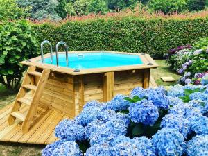una bañera de hidromasaje de madera en un jardín con flores azules en Villa de charme parc fleuri, arboré et piscine à BIARRITZ, en Biarritz