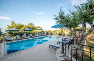 a swimming pool with lounge chairs and umbrellas at Aeolos Zante Villas with Heated Pool in Vasilikos