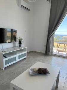 a living room with a white table and a tv at Blue Seaview Appartments in Paphos