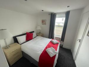 um quarto com uma cama com almofadas vermelhas e uma janela em PCK THAS HOTEL em Blackpool