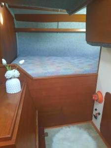 uma pequena cama num barco com uma secretária de madeira em Voilier logement spacieux à louer au port - Gruissan Plage - 11 Aude em Gruissan