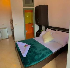 ein Schlafzimmer mit einem großen Bett und einer grünen Decke in der Unterkunft O-cyaneaalb in Vlorë