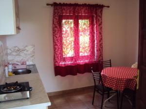 a kitchen with a table and a window with red curtains at Apartments Papan in Petrovac na Moru