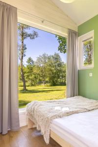 a bedroom with a bed and a large window at Lumi Resort Domki letniskowe z podgrzewanym basenem in Rewal