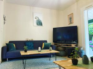 ein Wohnzimmer mit einem blauen Sofa und einem TV in der Unterkunft Villa de charme parc fleuri, arboré et piscine à BIARRITZ in Biarritz