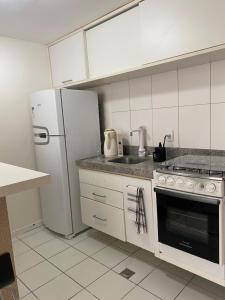 Il comprend une cuisine équipée d'un réfrigérateur blanc et d'une cuisinière. dans l'établissement Vitoria Loft 403, à Salvador