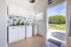 uma cozinha com armários brancos e uma grande janela em Lumi Resort Domki letniskowe z podgrzewanym basenem em Rewal