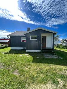 a small house on a lawn with a cloudy sky at Lyngen House in Olderdalen