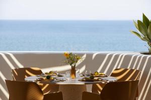 a table with a plate of food on a balcony with the ocean at PAROCKS Luxury Hotel & Spa in Ambelas