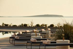a row of tables with towels on them next to the water at PAROCKS Luxury Hotel & Spa in Ambelas