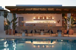 a restaurant with a bar with chairs and a swimming pool at PAROCKS Luxury Hotel & Spa in Ambelas