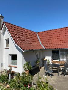 a white house with a red roof and chairs at Ott‘s FEWO in Gnevsdorf