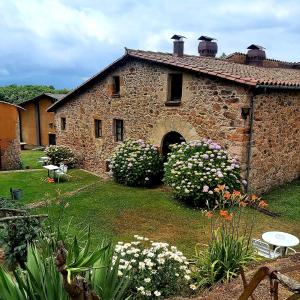 an old stone building with a yard with flowers at Mas Cal Sastre in Sant Hilari Sacalm
