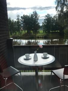 a table with two cups and a vase with a flower at Apartmán Plovárna in Kamenice nad Lipou