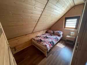 a small bedroom with a bed in a wooden cabin at Uweronci in Ustrzyki Dolne