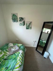 um quarto com uma cama e um espelho em 5min Drive to Luton Airport, 2 Train Stations & Motorway - FREE PARKING - LATE CHECK OUT 11AM - Quiet & Peaceful Location with a relaxing Garden - ONLY 25min drive to North LONDON - FREE WIFI em Luton