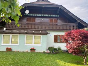 uma casa com um relógio na frente em HIDE-AWAY Corinna em Drobollach am Faakersee