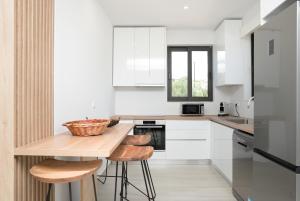 a kitchen with white cabinets and a table with stools at Ariadne Elegant Villa in Psarou