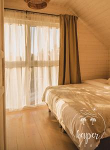 sypialnia z łóżkiem i oknem z zasłonami w obiekcie Kaper Łeba - Domki Nad Morzem w Łebie