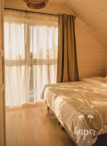 a bedroom with a bed and a window with curtains at Kaper Łeba - Domki Nad Morzem in Łeba