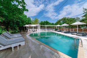 a swimming pool with lounge chairs and umbrellas at Inspira Boutique Hotel Thassos - Adults Only in Prinos