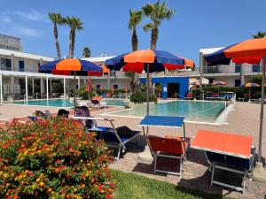 a resort with chairs and umbrellas and a swimming pool at SALENTO - Casa vacanza - Torre dell’orso in Torre dell'Orso