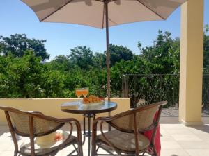 einen Tisch und Stühle mit Sonnenschirm auf einer Terrasse in der Unterkunft BELLA CISTERNA in Kambos