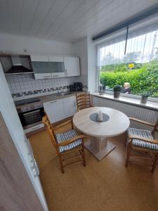cocina con mesa, 2 sillas y ventana en Meeresleuchten, en Krummhörn