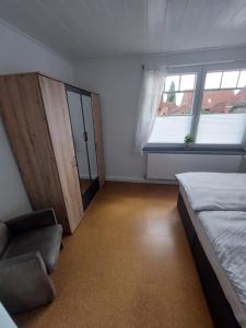 1 dormitorio con 1 cama, 1 silla y 1 ventana en Meeresleuchten, en Krummhörn