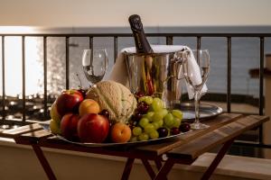 a plate of fruit on a table with wine glasses at Stella Ví in Cefalù