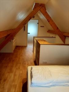 a attic room with a bed and a door at Vakantiehuis Boomgaard in Vrouwenpolder