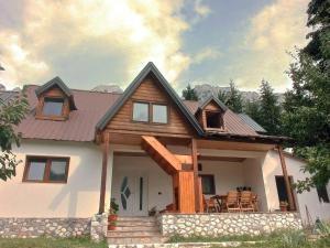 a house with a wooden roof with a table and chairs at Bujtina Albjoni in Valbonë