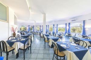 a restaurant with blue tables and chairs and windows at Bristol Hotel in Ischia