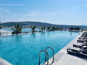 a large swimming pool with lounge chairs and the water at Soliport Hotel & SPA in Alaçatı