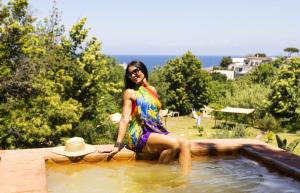 a woman in a colorful dress sitting in a swimming pool at Bristol Hotel in Ischia