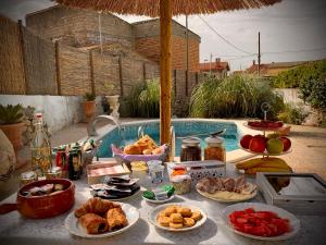 een tafel met borden eten naast een zwembad bij Sa domu de don Ninnu bed breakfast Spa in Gesturi