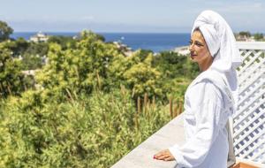 a woman standing on a balcony looking at the ocean at Bristol Hotel in Ischia